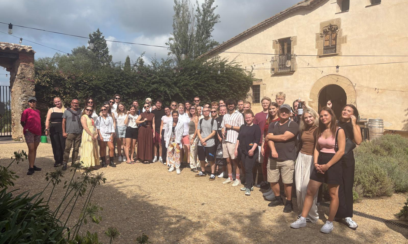 Študenti programa Erasmus+ so se zbrali pred stavbo v živahnem zunanjem okolju.