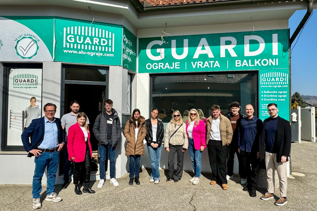 Team gathered in front of the Guardi logo, smiling for a group photo