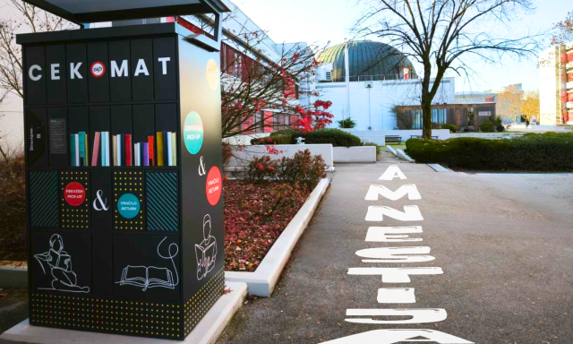 CEKomat pred Knjižnico CEK, ob katerem je na tleh velik napis »AMNESTIJA«, ki napoveduje akcijo vračila knjižničnega gradiva brez zamudnin v času amnestije.