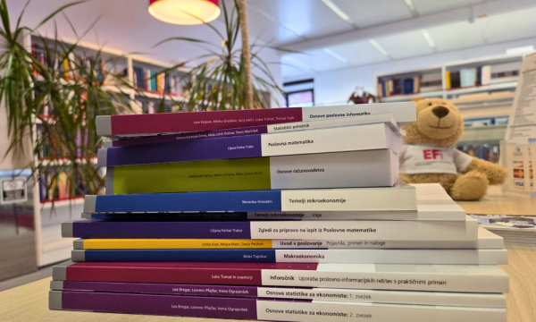 Paket študijskih gradiv za 1. letnik, razstavljen na pultu v Knjižnici CEK. V ozadju je plišasti medvedek EFi. Slika spremlja predstavitev akcijske ponudbe paketov študijskih gradiv za bruce UL EF.