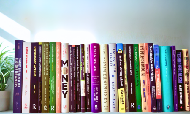 A shelf with the latest books arranged upright, a small potted plant at the side and soft natural light coming from the left.