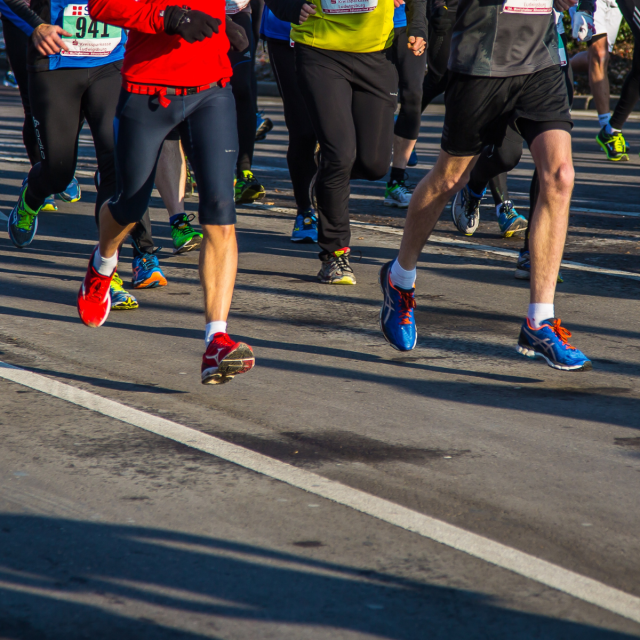 Udeleženci maratona tečejo naprej, pri tem pa kažejo energijo in navdušenje.