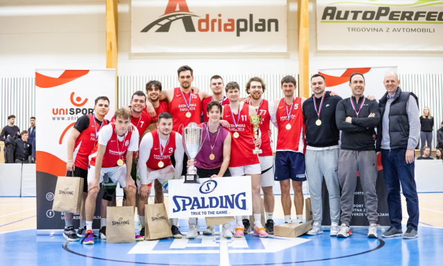 Moški v rdečih in belih dresih stojijo skupaj, z nasmehom na obrazu razkazujejo svoje pokale in proslavljajo svoj uspeh.