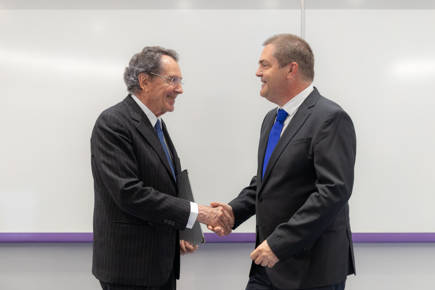 Prof. Gian Maria Gros-Pietro and the Dean of UL SEB, Prof. Tomaž Turk shake hands, with a white school board in the background.