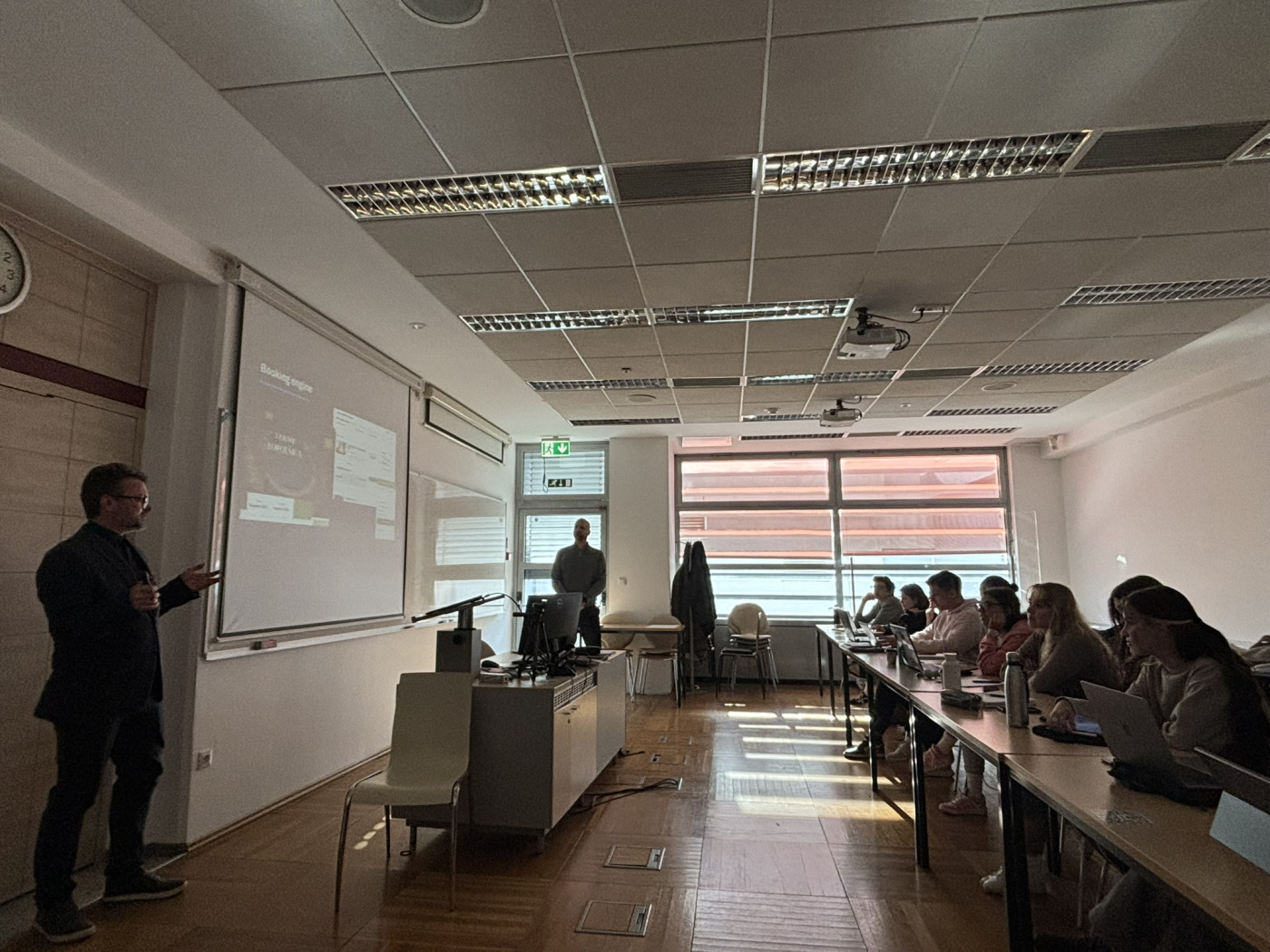 Profesor predava v učilnici, ki je napolnjena s študenti.