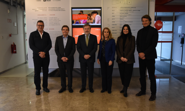 A group of people in fomral outfits poses in the hallway.