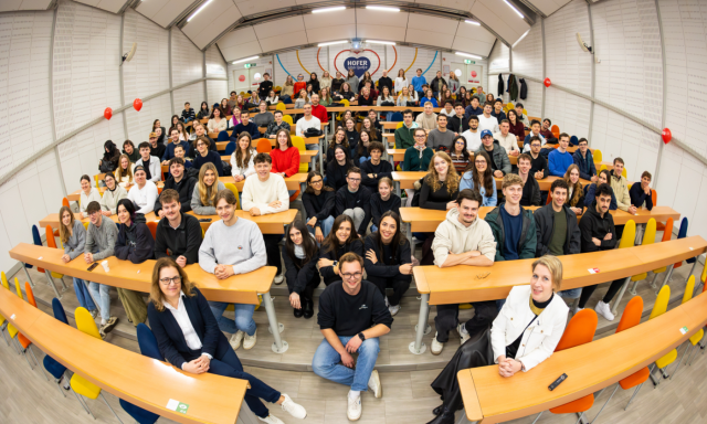 A group of international students and staff from the international office posing together in a classroom for a photo.