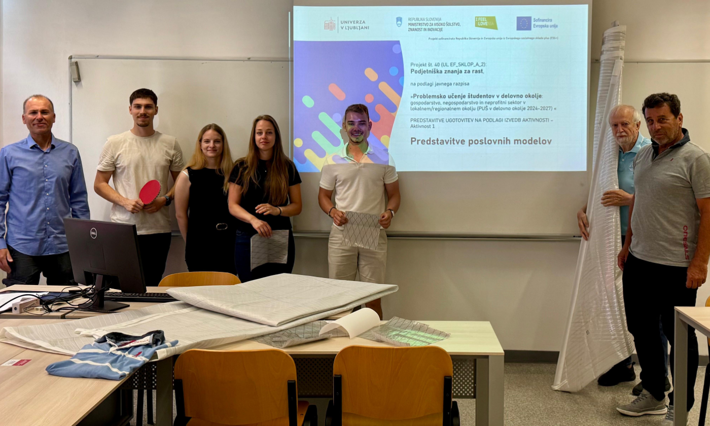 Skupina ljudi stoji pred projektorjem po zaključku predstavitve projekta.