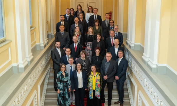 Skupina formalno oblečenih ljudi pozira za fotografijo na velikem stopnišču.